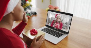 African american woman with santa hat using laptop for christmas video call with woman on screen. christmas, festivity and communication technology.