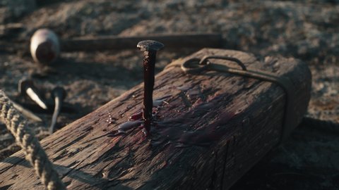 Metal nail covered with blood and stuck in wooden cross after Jesus Christ crucifixion