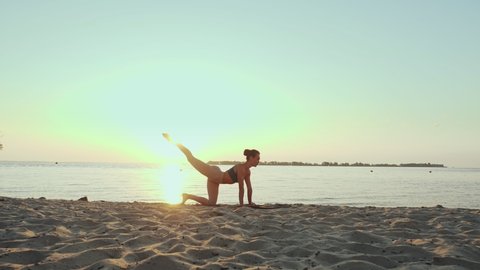 barre workout. stretching outdoors. yoga beach. Athletic young woman is doing exercises on mat, at the beach during sunset or sunrise. Fitness training outdoors. Fitness, ballet, sport, yoga and