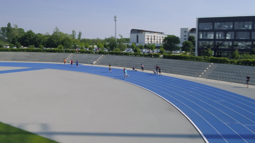 Relay runners passing batons on track from above.