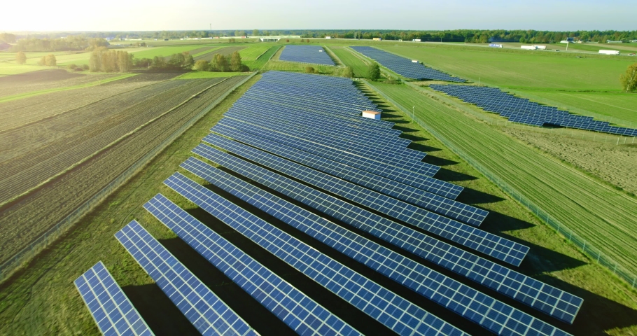 Aerial view of solar panels in a solar park used for clean energy production. Alternative source of electricity from the sun. Rows of modern photovoltaic solar panels in the green fields. Royalty-Free Stock Footage #1082292466