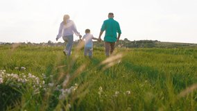 Happy family at sunset walking down the field and enjoy the moment together young parents and their child together speeding time