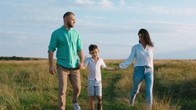 Beautiful moments of a young family parents and one cute little boy enjoy the sunset and feeling the wonderful of nature together walking in front of the camera holding hands. Shot on ARRI Alexa Mini.