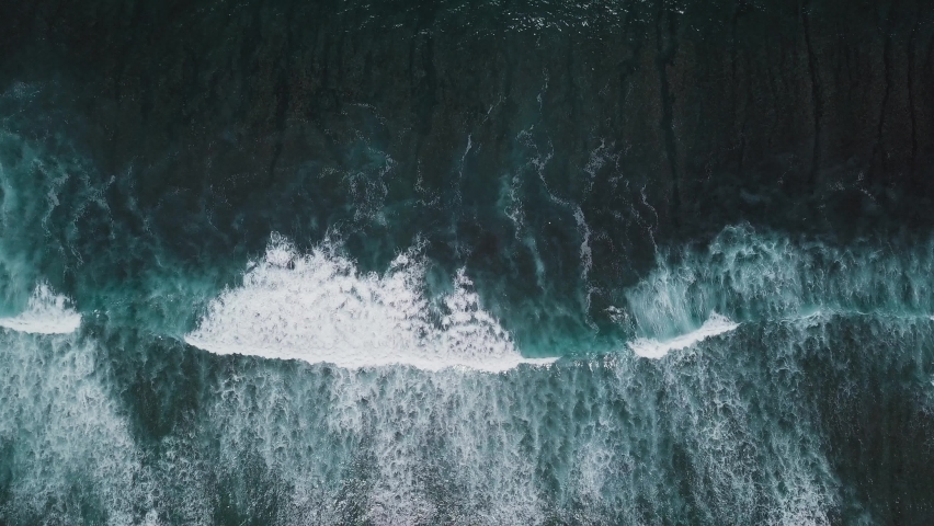Waves rolling from above. Top down 4k drone view on blue turquoise ocean, breaking waves, whitewash. Huge swell hitting shoreline. Bali, Indonesia Royalty-Free Stock Footage #1082293987