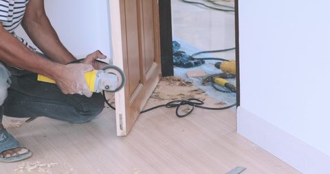 Carpenter man working on the wooden door with wood machine in new house