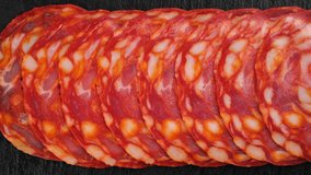 Chorizo sausages top view on black background. Sliding shot. 4K UHD video