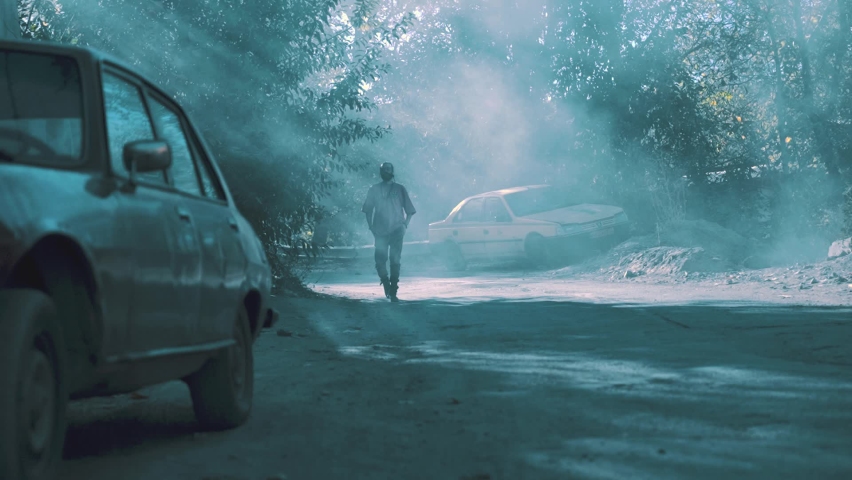 Cinematic view of a young man walking in autumn nature next to a car 