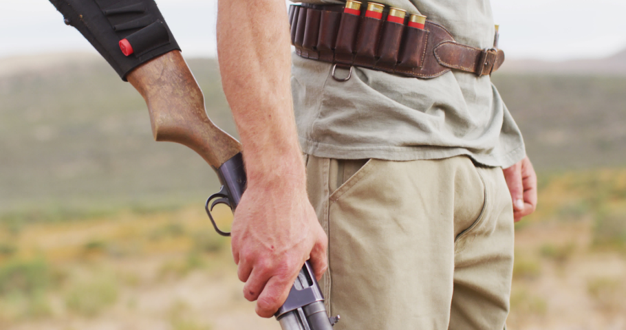 Caucasian male survivalist holding hunting rifle, looking to distance in wilderness, smiling. exploration, travel and adventure, survivalist in nature.