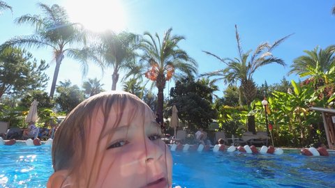 a little girl in a pink swimsuit swims and has fun in the pool. entertainment and fun for children in the hotel's swimming pool. swimming training. turkey, antalya, 11.11.2021