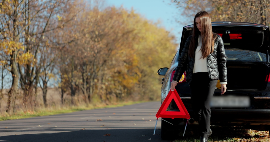 Sad disappointed woman on broken car. Woman driver installing red triangle sign. Broken car accident. Woman driver places emergency stop sign. Royalty-Free Stock Footage #1082304658