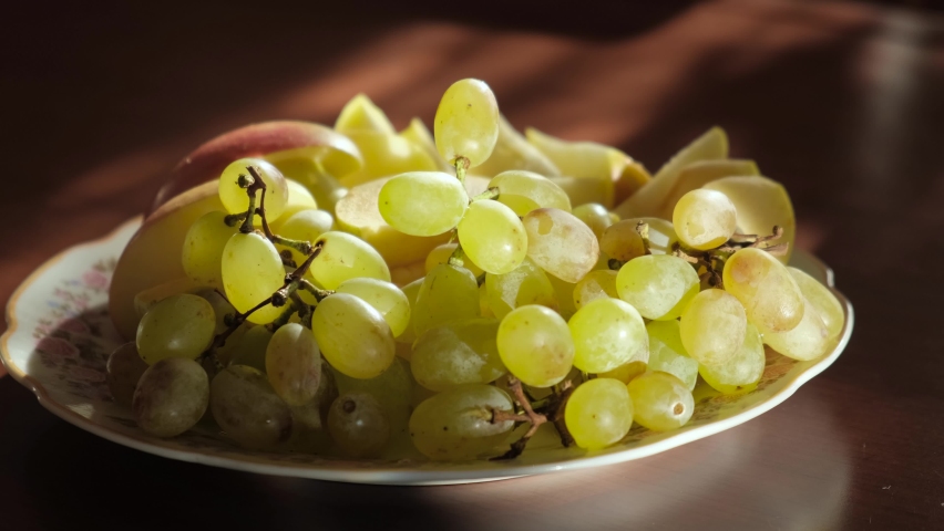 Man eating fresh grapes from a plate of fruit, close-up