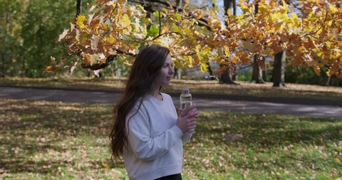 Eco-friendly girl drinks water from a reusable glass bottle. Zero waste and less plastic lifestyle