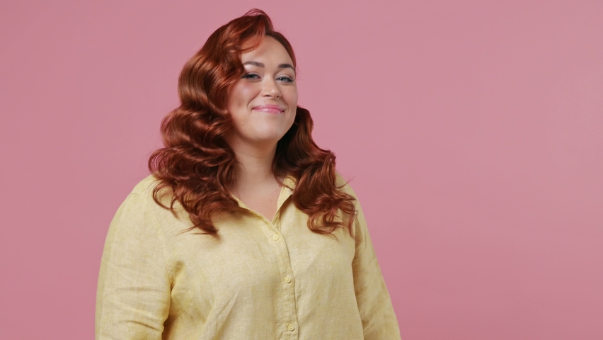 Fun young ginger chubby overweight woman 20s years old wears yellow shirt dance waving rising expressive gesticulating hands have fun enjoy celebrate isolated on plain pink background studio portrait