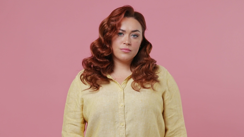Serious strict severe sad young ginger chubby overweight woman 20s years old wears yellow shirt say no hold palm folded crossed hands in stop gesture isolated on plain pink background studio portrait Royalty-Free Stock Footage #1082308597