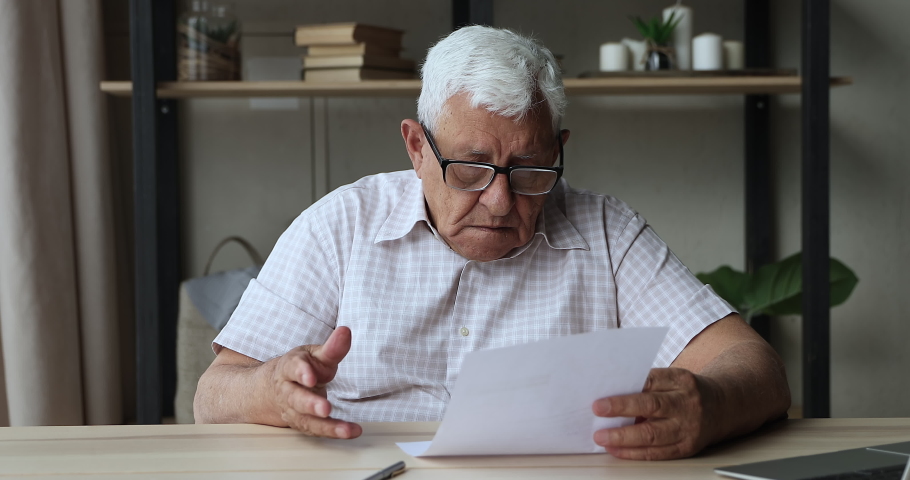 Concerned frightened elderly male get official bank notification read about bankruptcy debt feel confused worried. Stressed middle aged man retiree troubled with unexpected bad news from paper letter Royalty-Free Stock Footage #1082309539