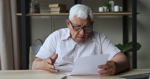 Concerned frightened elderly male get official bank notification read about bankruptcy debt feel confused worried. Stressed middle aged man retiree troubled with unexpected bad news from paper letter