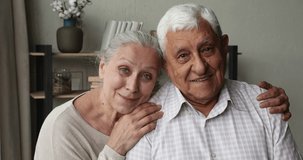 Headshot portrait happy older age spouses affectionate retired wife hug shoulders of beloved hoary husband. Loving mature couple posing together smiling looking at camera then aside dreaming imagining