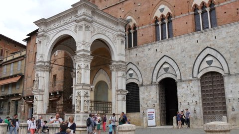Siena, Tuscany, Italy JULY, 15, 2016 Cappella di Piazza of Palazzo Pubblico, the town hall, in Piazza del Campo Siena's main square with tourists. The Palio di Siena takes place in this square.