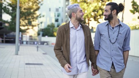 Happy Gay couple having fun, talking and walking together holding hands in the city