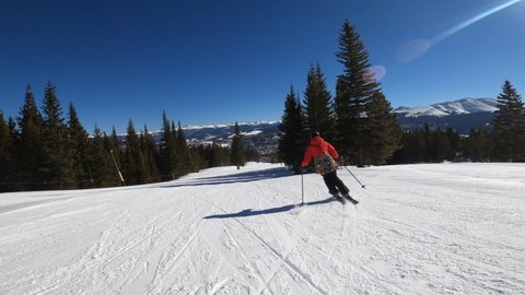 Skier in red jacket going downhill on a high speed in Breckenridge Ski Resort Colorado.