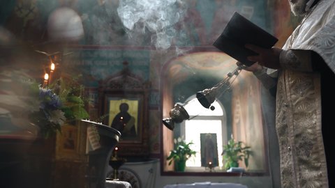 The priest waves a censer dispersing the smoke with incense in the temple. Filming the ceremony