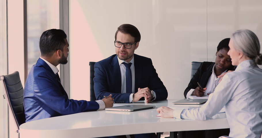 Diverse businesspeople gather in modern office boardroom sit at table discuss business, multi ethnic entrepreneurs in suits reached agreement shaking hands accomplish formal meeting. Make deal concept Royalty-Free Stock Footage #1082322403