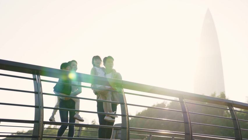 young asian family with two children standing on bridge looking at view outdoors in city park Royalty-Free Stock Footage #1082326507
