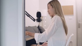 Beautiful Young Asian woman podcaster recording podcast and live streaming content for social media at home studio.