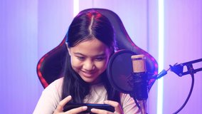 Excited Asian Kid Girl Playing Video Game With Mobile Phone Then Smiles To Camera While Live Stream
