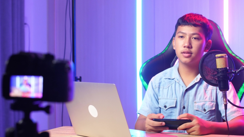 Asian Kid Boy Holding Mobile Phone And Talking To Camera While Live Stream
