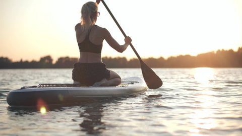 Girl Stand Up Paddle Boarding. Warm Summer Beach Vacation Holiday. Travel Paddles Paddleboard. Sup Board Journey. Young Woman Relaxing On Sup Surf Swimming. Watersport Floating On Surfboard At Sunset