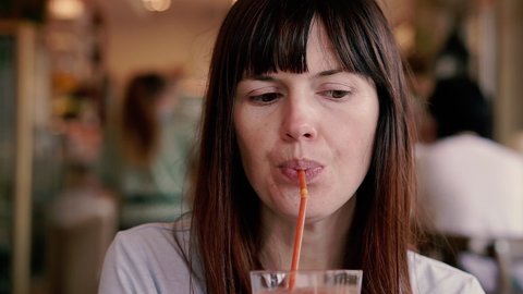 Tomato juice. A woman drinks tomato juice through a straw.