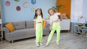 stylish girlfriends in similar clothes dance to music at home, children shoot videos for social networks and show thumbs up