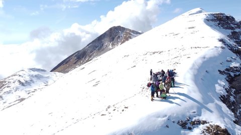 Aerial video from a drone, active hikers in the snow-capped Caucasus mountains of Abkhazia, on the Arabica plateau. Young people conquer the snowy peaks of the Caucasus.