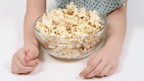 Girl eats popcorn from a transparent glass bowl. Extreme close-up. 4K UHD video footage 3840X2160.