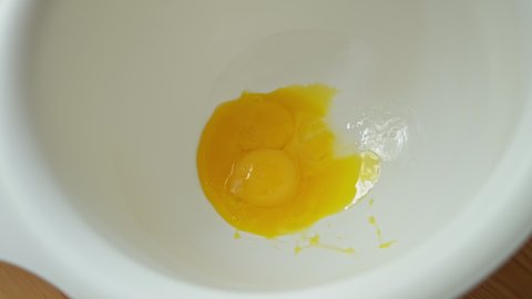 the egg yolk slowly falls into a white bowl, separates the yolks from the whites and puts them in whipping bowls. the process of creating a pie.  the process of creating baking. Close-up. Slow motion