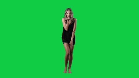Super slow motion of young woman in black silk sleepwear blowing a kiss at camera. Full body isolated on green screen background