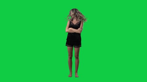 Super slow motion of playful young woman in sleepwear shaking head tossing hair. Full body isolated on green screen background