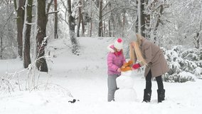 Winter fun. Happy mother with her daughter are building a snowman in a snowy park. Lovely family at winter holidays. - Powered by Shutterstock - Get 15% off with code: PIKWIZARD15