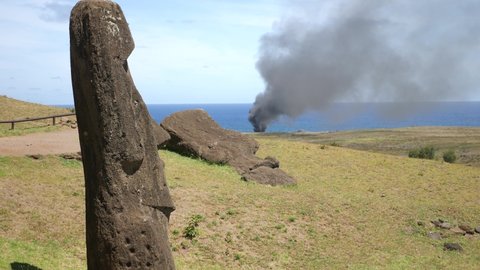 Mysterious Moai statues on fire. Ancient statues made of black volcanic rocks under the inactive volcano on Easter Island. exotic island landscape and Giant megalith Moai statues. 4K Rano Raraku.