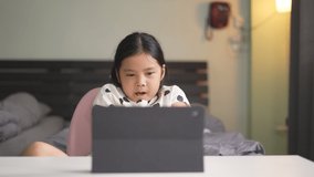 Asian child student learning on computer and sleepy yawn or kid girl studying online class by video call and twisting stretch oneself or person learn from home on back to school by tablet in bedroom