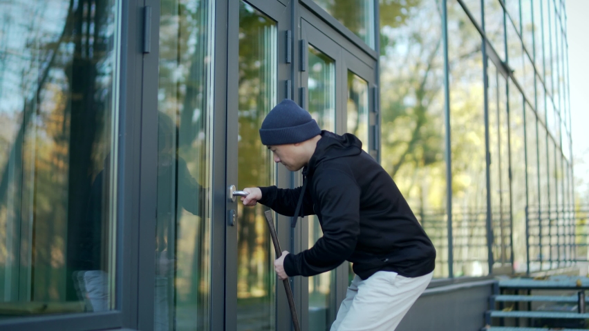 robber tries to break open the door of the house or office but he fails to hear the alarm runs away. thief  broke breaking. bandit sneaks. intruder trying to force a door lock using a crowbar Royalty-Free Stock Footage #1082357395