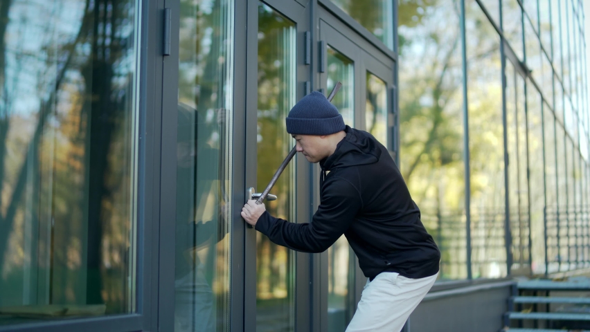 robber tries to break open the door of the house or office but he fails to hear the alarm runs away. thief  broke breaking. bandit sneaks. intruder trying to force a door lock using a crowbar Royalty-Free Stock Footage #1082357395