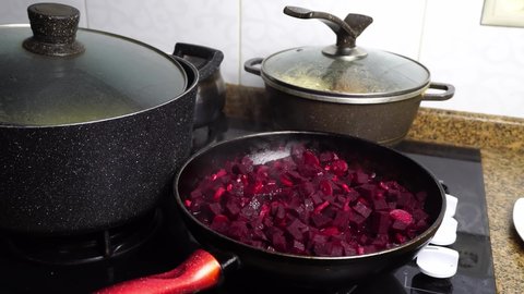 Cooking beetroot in a frying pan. Roasting for cooking borscht. Ukrainian cuisine. Mixing of crushed beets on a gas stove. Preparation of salad or soup.