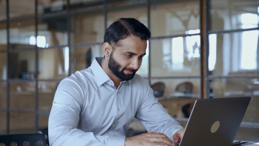 Indian ethnic business man employee professional manager using computer, typing, analyzing digital data working in modern office doing online data market analysis planning looking at laptop. | Shutterstock HD Video #1082359507