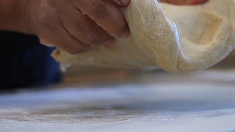 Hand kneading dough for rolls, bread, pizza or pastries - isolated close up in slow motion