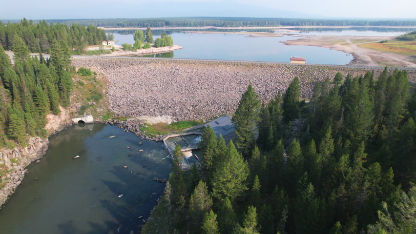 Beautiful aerial view of a dam and lake in Island park Idaho. Also seeing a wide of a small hydroelectric plant at the bottom and start of the river
