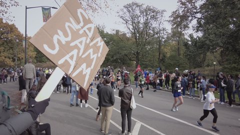 New York City, USA - Nov 7, 2021: 2021 TCS New York City Marathon runners and groups of spectators cheering. "SAM SAM SAM" sign in foreground. In Central Park during the final stretch.