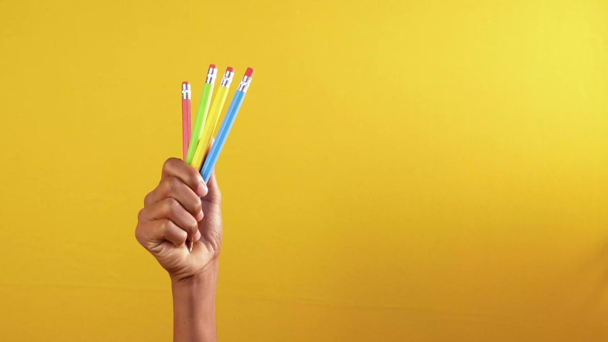 child girl holding many color pencils against yellow background 