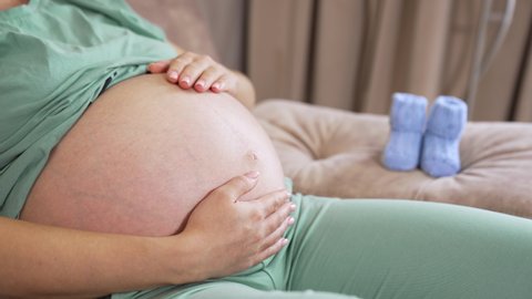 будущая мама отдыхает на диване и гладит живот